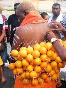 A devotee getting oranges hung to his back with hooks